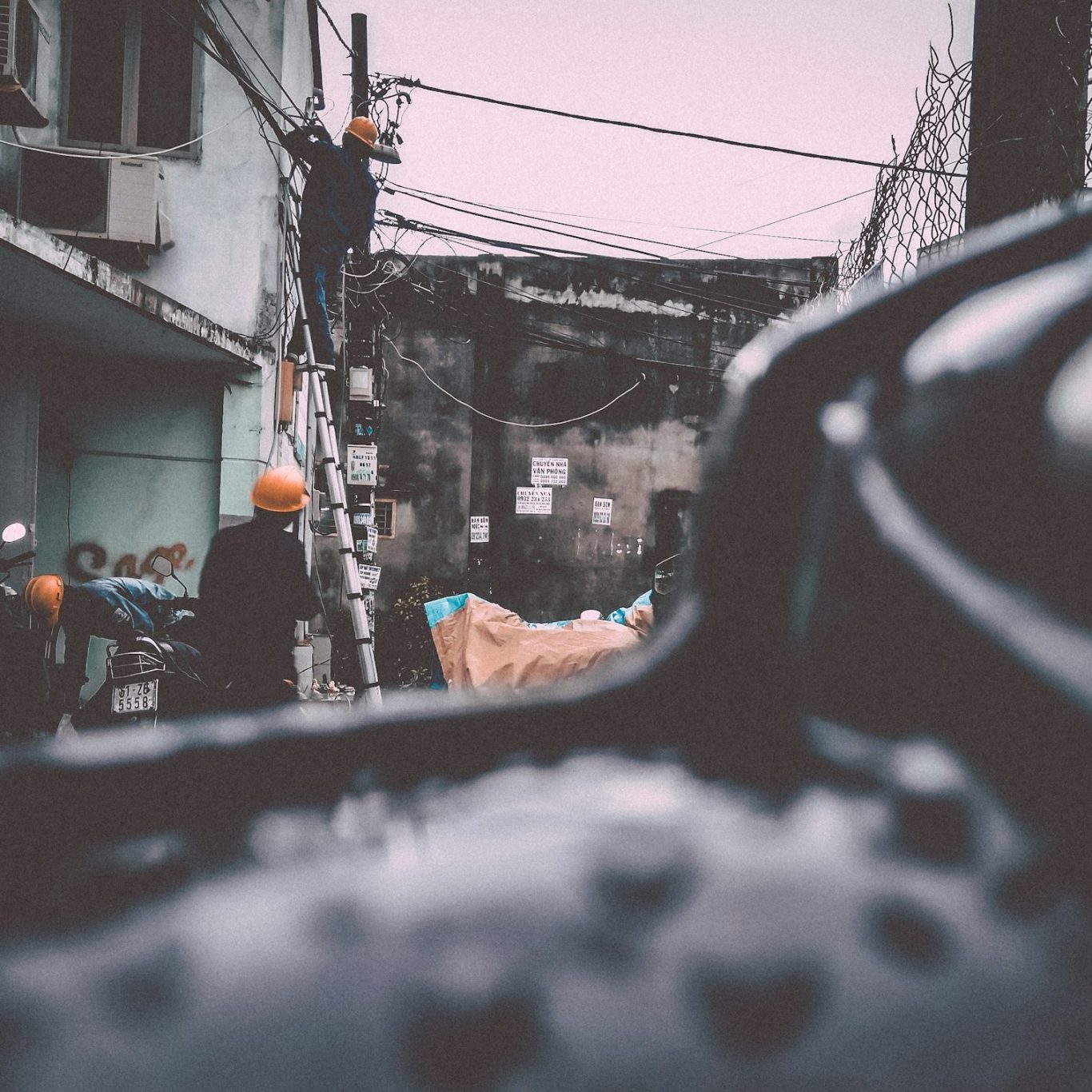 energy efficiency consulting Electricians on ladders surveying electrical wires on the exterior of a house.